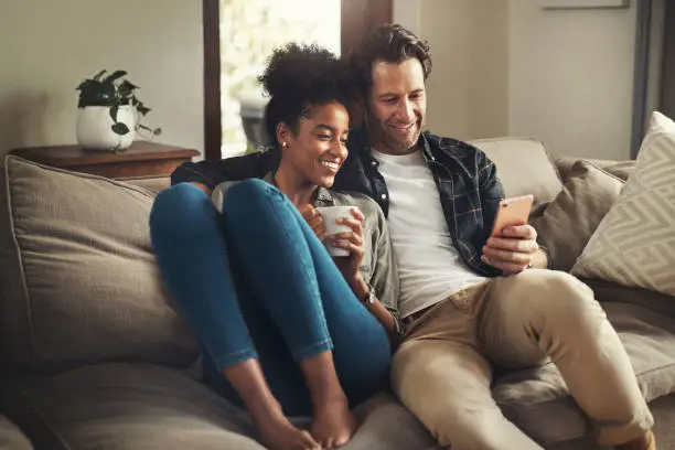 Shot of a happy young couple using a digital tablet while relaxing on a couch in their living room at home